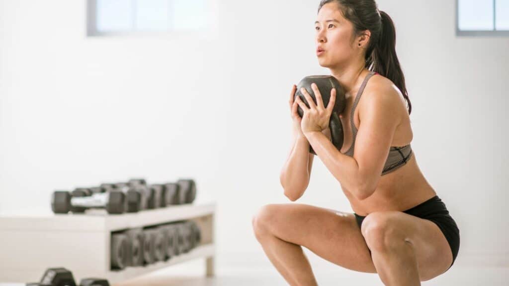 Photo of woman doing deep squat with weight